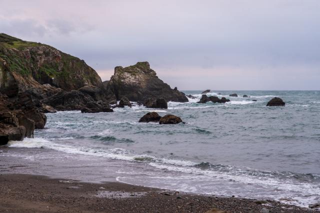 Rocks stretch from a beach into the sea. [Fuji X-T5 / Sigma 17-40 1.8]