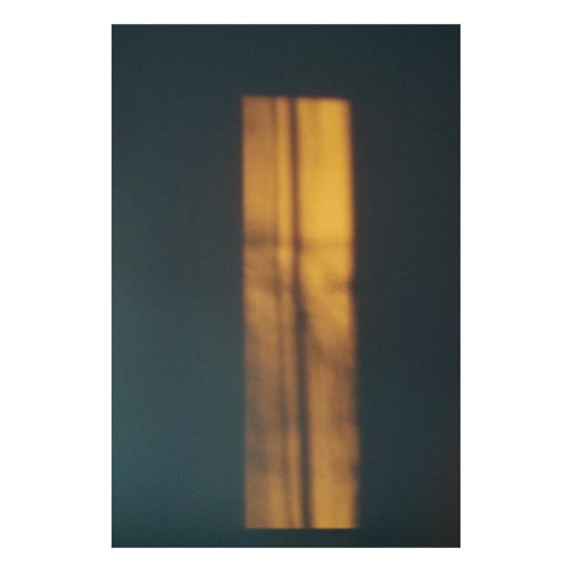 A photograph of a white wall in the early morning, with sunlight streaming through the window and illuminating the wall. The photo is processed in a Kodak Portra style.