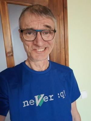 Geek guy in a T-shirt that has the text "neVer :q!" on where the V is the Vim logo.