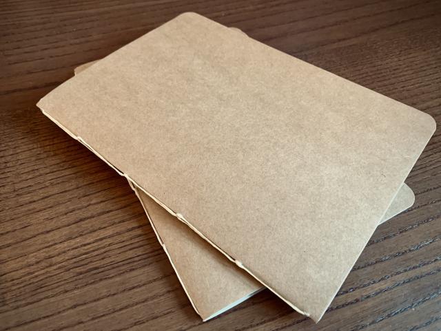 A couple of cardboard and paper notebooks