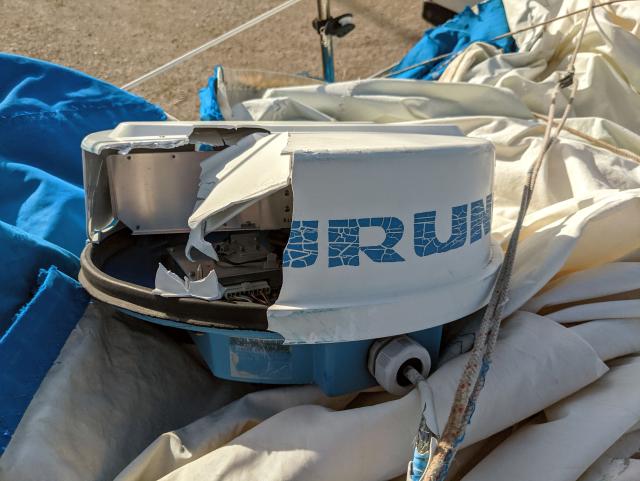 A Furuno sailboat radar, broken, laying on a torn genoa.