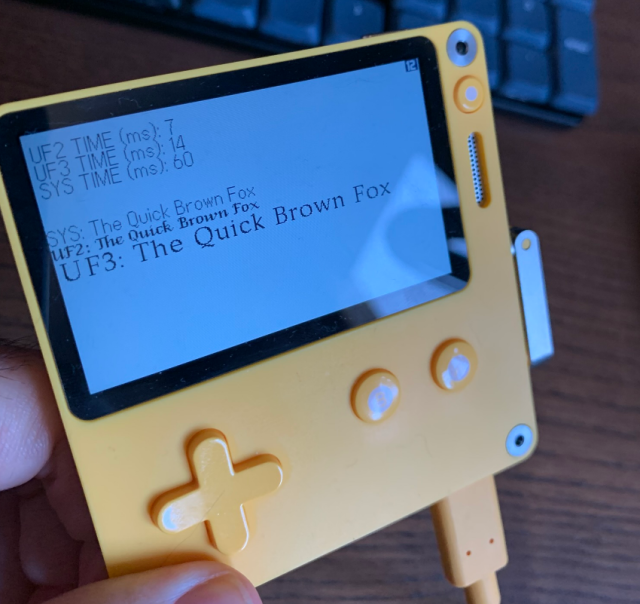 A playdate console showcasing a UF2, UF3 and system font rendering some text and the performance (in ms) of running the drawing 100 times.