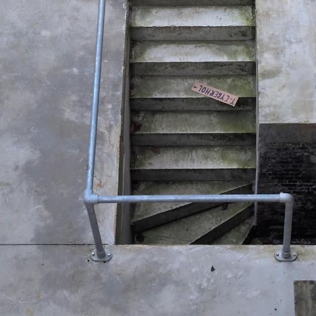staircase leading down with a cardboard sign on one step reading: T-CYBERHOL →