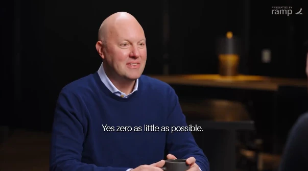 A podcast still featuring far-right tech billionaire Marc Andreessen boasting that he does zero introspection in his life. He is wearing a blue sweater and collared shirt and his prominent cone-shaped head is shining in the studio light. He is holding a black coffee cup with both hands.