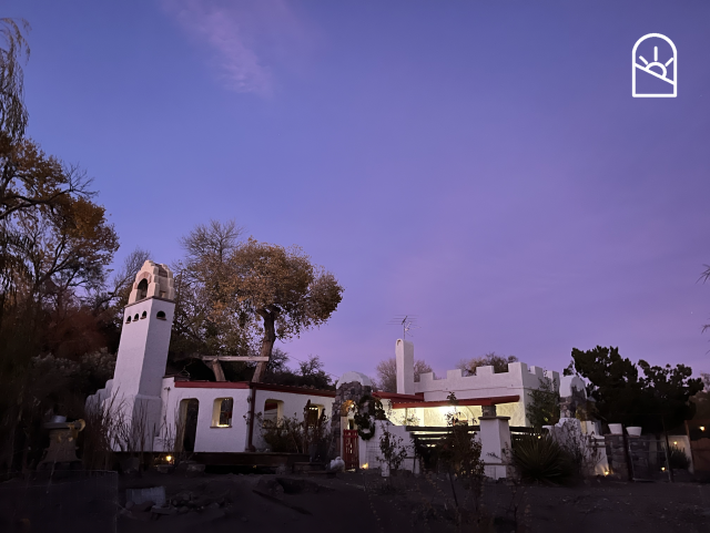 a hodgepodge adobe house against a purple sky