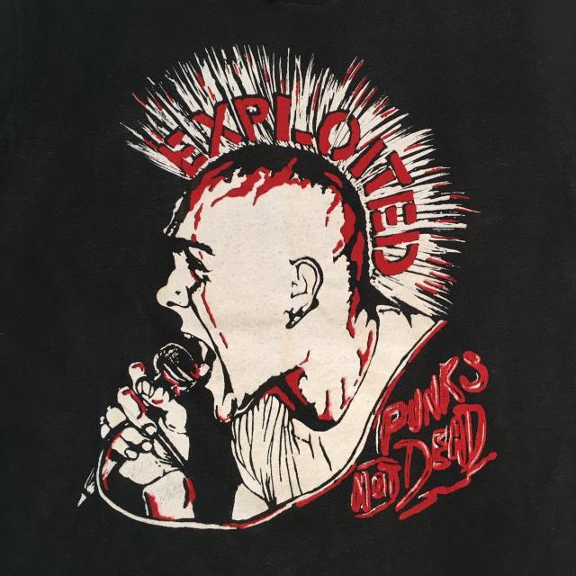 In a drawing in red and white, the lead singer of the UK Punk Band, The Exploited, holds a microphone with his mouth wide open and a mohawk that reads "Exploited".  Stylized text of "Punk's Not Dead" appears in the far right corner.
