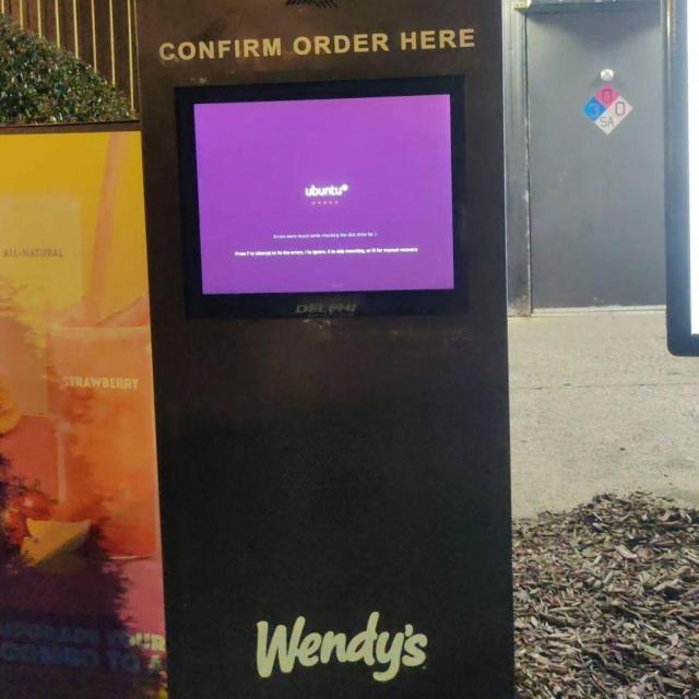 This picture shows a wall with a monitor inside it running Ubuntu. Below, one can see the Wendy's logo.