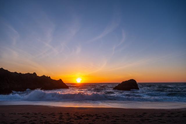 The sun creeps down behind rocks on the seashore. [Fuji X-T5 / Sigma 17-40 1.8]