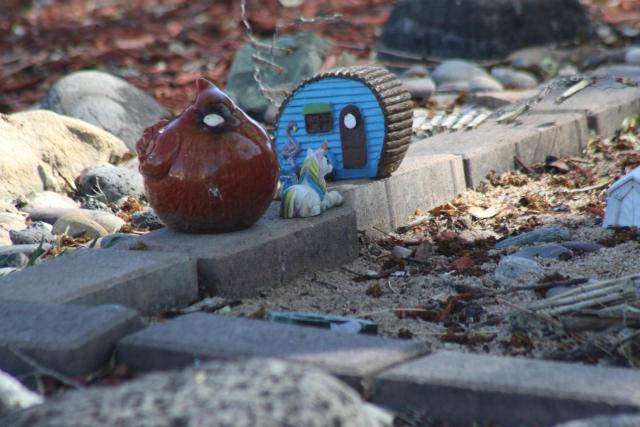 A cardinal figurine a toy unicorn and a toy camper on some pavers in someone’s yard