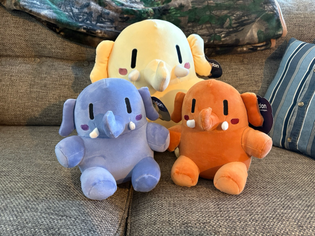 All three plushtodon plushies on a tan couch.