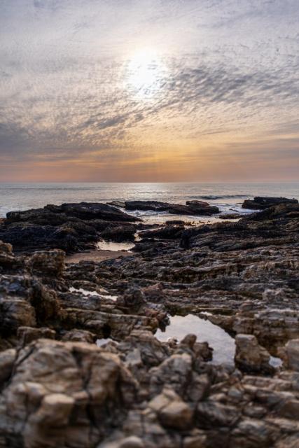 The sun sets over chunky rocks, with the sea behind. [Fuji X-T5 / Sigma 17-40 1.8]