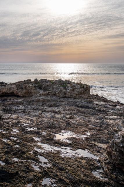 The sun sets over chunky rocks, with the sea behind. [Fuji X-T5 / Sigma 17-40 1.8]