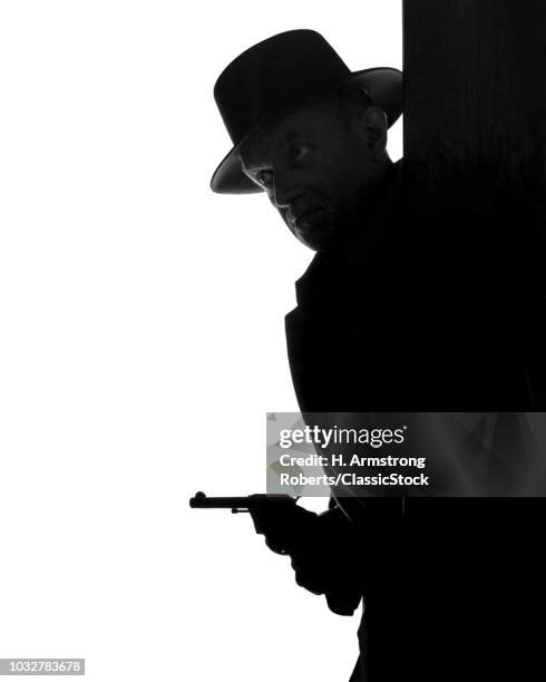 a stockphoto with some dark outline of a gangster coming around the corner with his fedora on and a pistol drawn