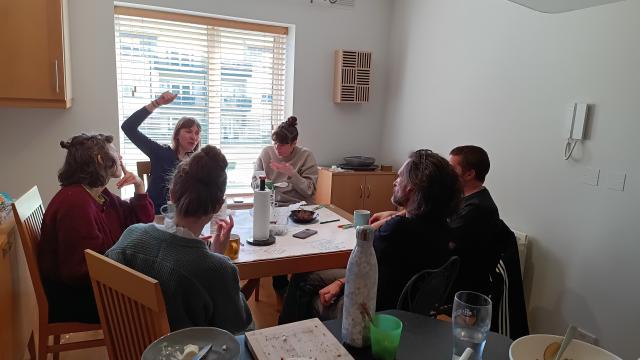 Artists around a table talking and eating and sketching ideas