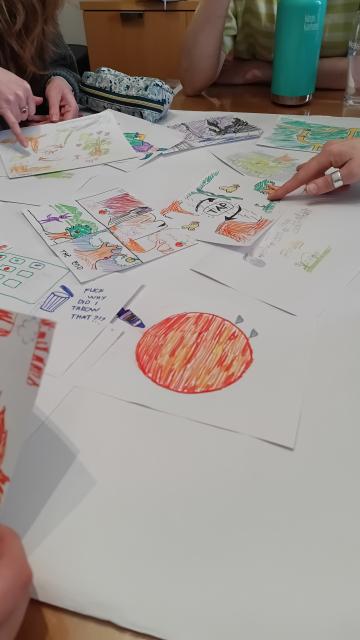 Drawings on paper scattered across a table