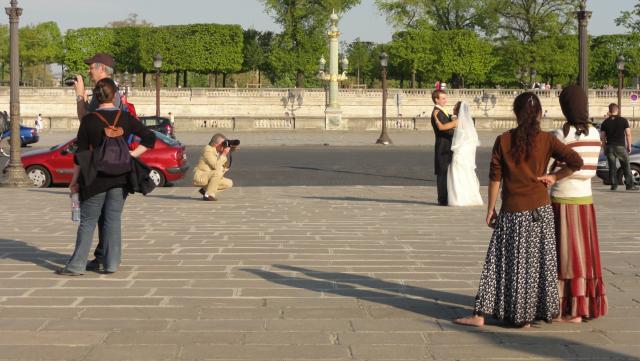 A paris un photographe prend en photo les mariés pendant que les touristes les regarde, ou pas