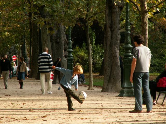 Un jeune joue au foot avec son père dans un parc à paris