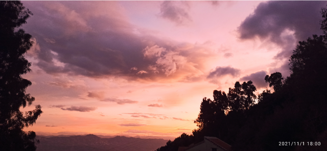 Couché de soleil. Ciel écarlate avec un flanc de montagne et un grand eucalyptus sur les deux côtés de la photos.