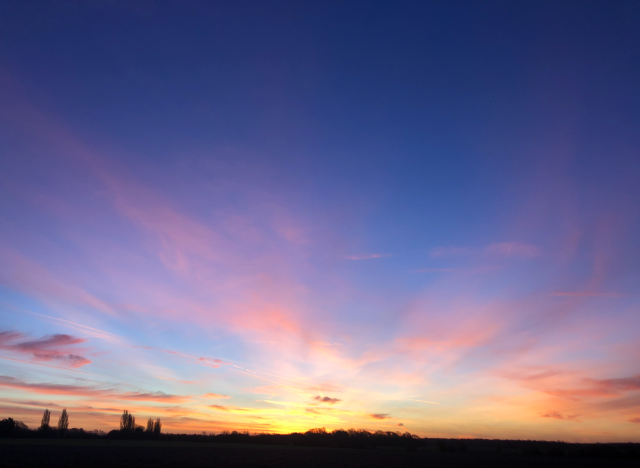 multicoloured pre-dawn sky. Orange, pink, yellow, with a vibrant blue above.
