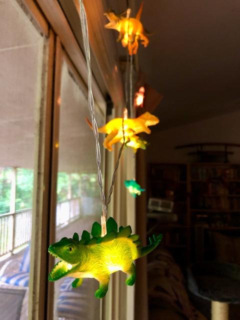 Plastic hollow dinosaurs, strung up with led lights in them over a doorway. The dinosaurs glow from within. 