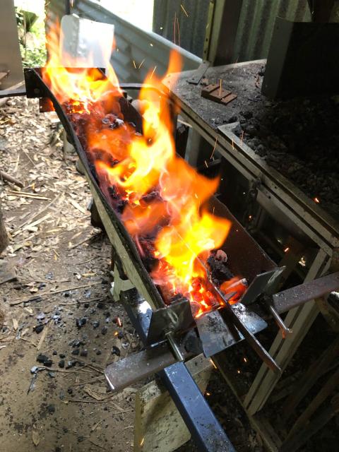 Sword blade nestled in the hot coals and flames of the forge