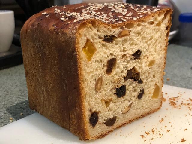 Partially cut loaf showing pieces of fruit amongst the crumb