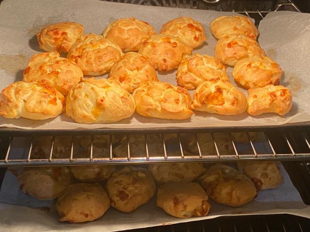 Two trays of cheese puffs (patè choux style) in the oven. 
