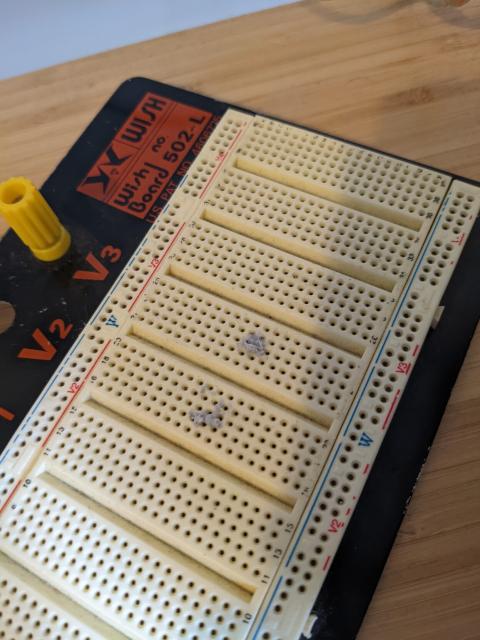 An electronics breadboard with two big smears of old blu-tac in the small component holes