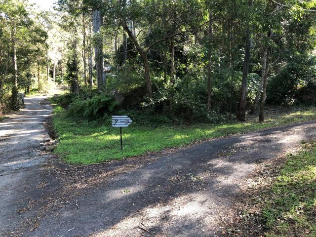 Corrugated iron sign mounted on a star picket. The sign contains the number 9 and an arrow, forged from horseshoes. In this photo the sign is further away so you can see the driveway split. 
