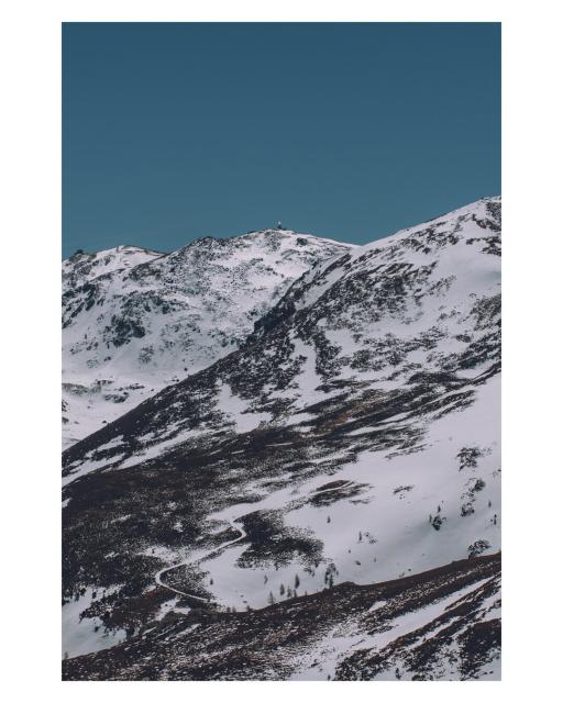 en: image shows mountain landscape partially covered in snow. there's a weather surveillance station on top of one of the mountains.

de: das bild zeigt eine teilweise verschneite berglandschaft. auf einem der berge befindet sich eine wetterüberwachungsstation.