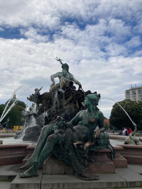 Impossibly baroque fountain, with voluptuous naiad in front, Neptune at center, sea creatures spouting water