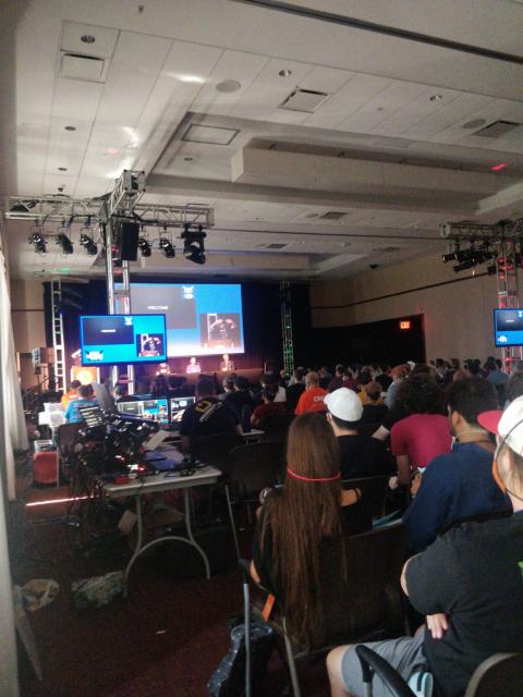 Welcoming ceremony with lots of AV equipment and a packed room of masked hackers