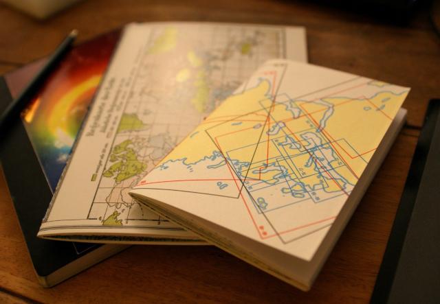 Two notebooks in A5 and A6 format on a table, with maps as outer covers