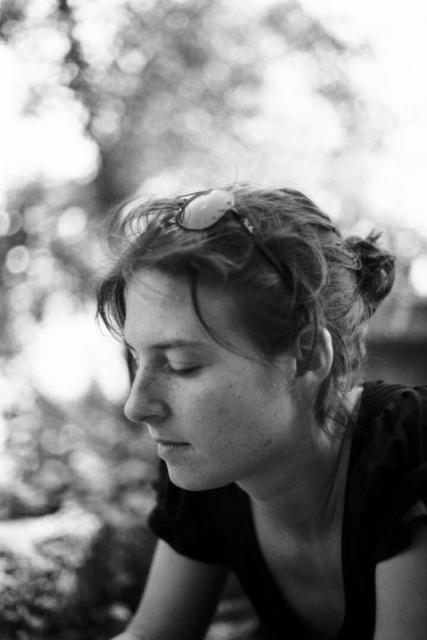 A portrait of a woman wearing sunglasses on her head and a blurry bokeh style background.