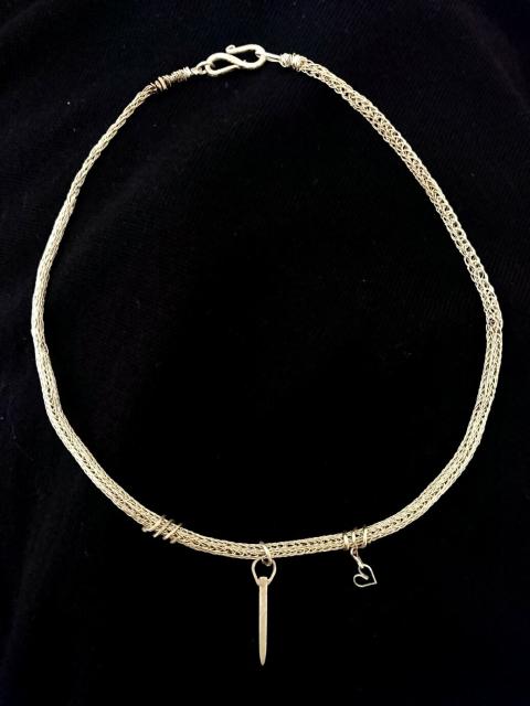 Knitted silver chain with a small elongated pendant and simple ornaments on each side