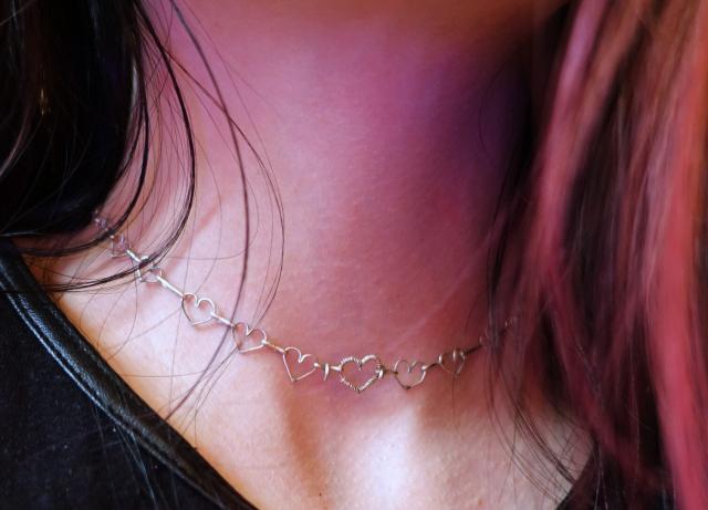 Person wearing the necklace. Only their neck and hair are visible. The chain has the lenght of a choker as it fits exactly around the neck. 