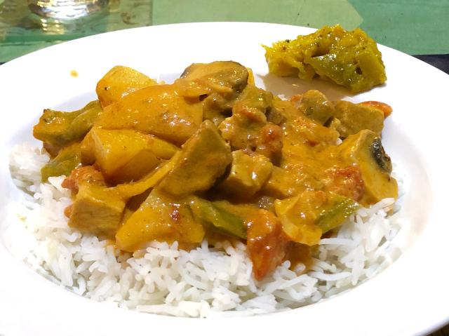 Pork curry on rice with a blob of lime pickles on the side. 