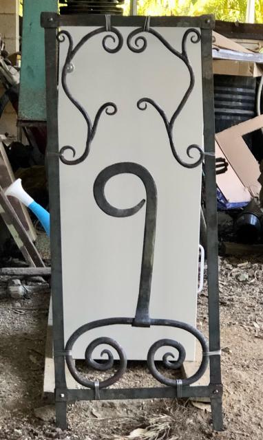 Steel frame riveted together, with a large 9 sitting on a double spiral and teo near identical scroll work pieces in the top corners. 