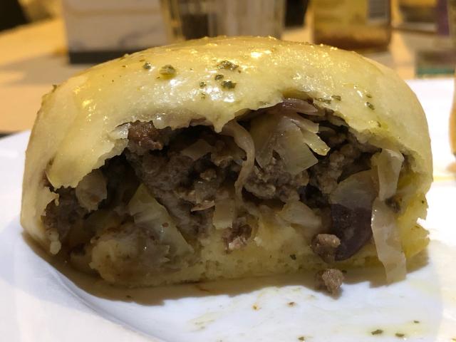 A bieroch cut open to reveal the inside of ground beef and cabbage. 