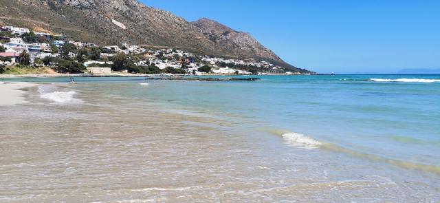 A beautiful blue - green ocean and sandy beach under a clear blue sky