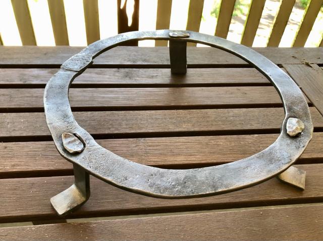 28cm diameter steel trivet made from a forge welded ring and the 6cm high legs attached via tenon and peening. 