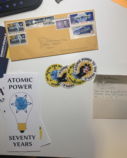 A recipient's photo of mail I sent out, showing stickers and pamphlets advocating nuclear energy, and space postage stamps.
