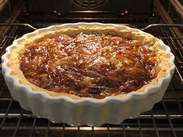 A fluted edge open tart filled with caramelised onion on a layer of blue brie. 