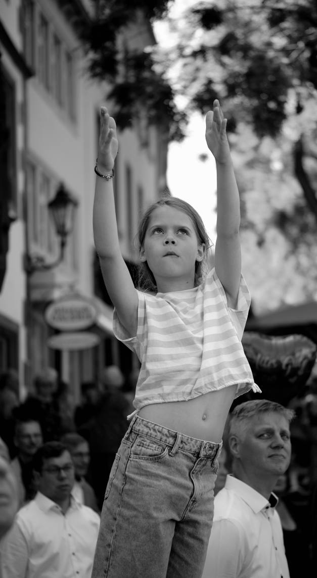 Ein Kind zeigt mit beiden Händen nach oben und blickt sehr konzentriert in die gleiche Richtung. Das Bild ist Schwarz-Weiß
