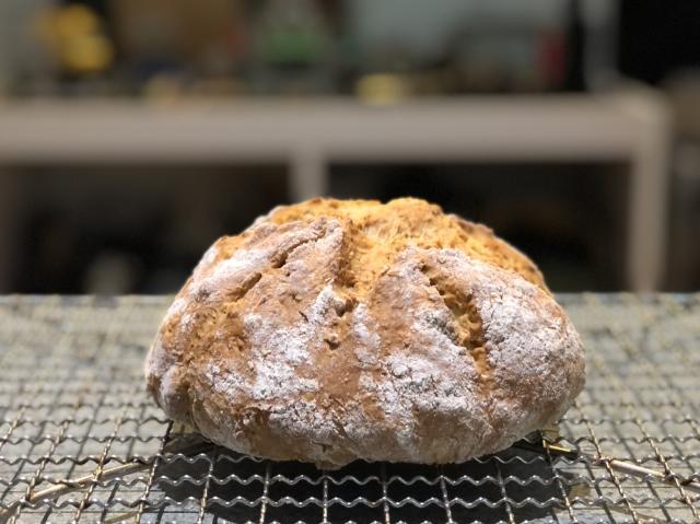 A small round loaf of soda bread on a wire rack. 