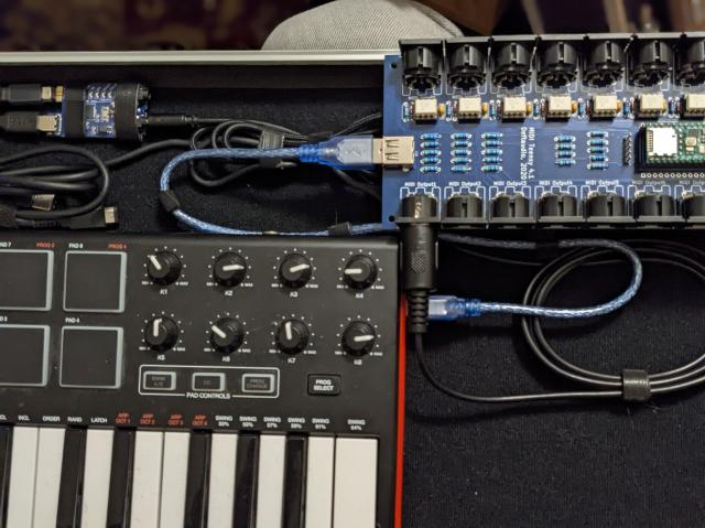 Photograph of keyboard, a couple of MIDI devices, and their respective cables secured down with velcro ties to a base made of the matching velco.