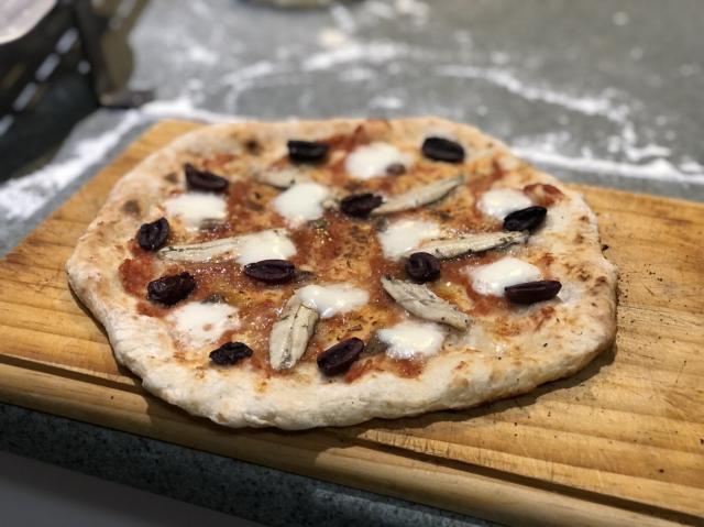 Anchovy pizza on a wooden board
