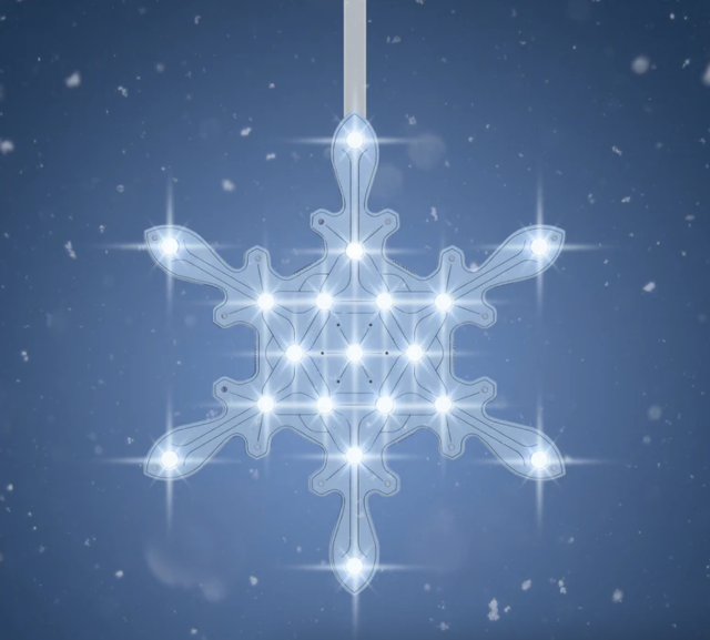 A snowflake shaped P C B with bright white L E D lights hanging against a light blue background