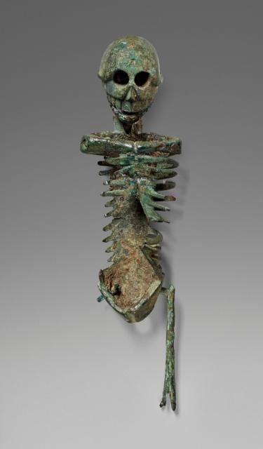 A bronze articulated skeleton, missing its arms and a leg. It has a green patina throughout