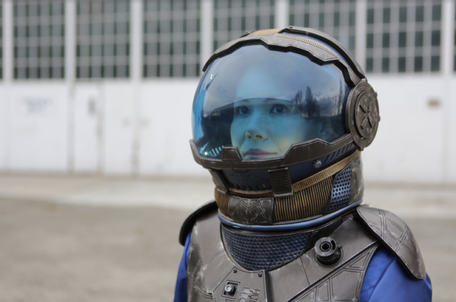 Sophy Wong wearing a blue tinted space helmet and staring off into the distance